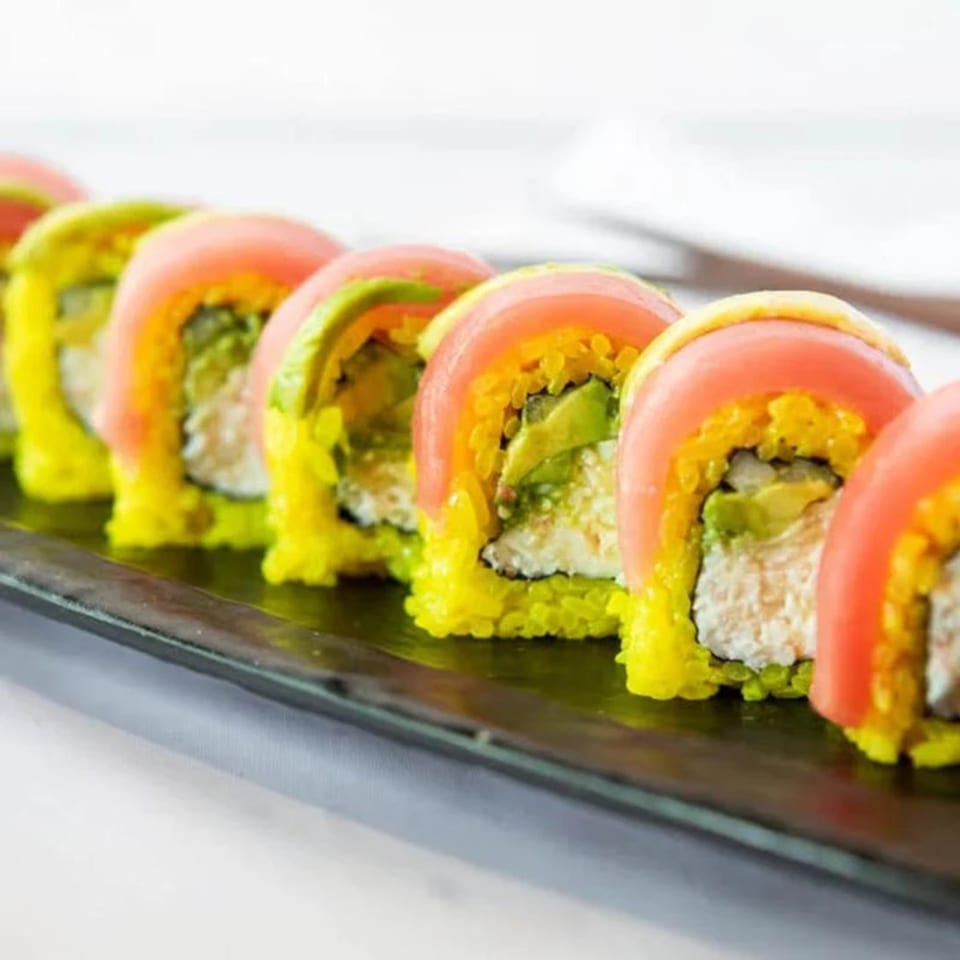 Niko Niko Sushi's colorful sushi rolls with pink fish and green avocado on a dark plate.