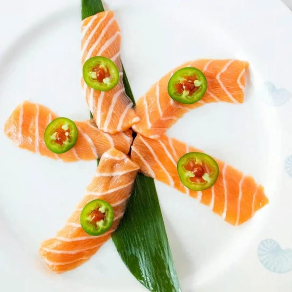 Niko Niko Sushi's salmon sashimi with jalapeño slices arranged in a star shape on a white plate.