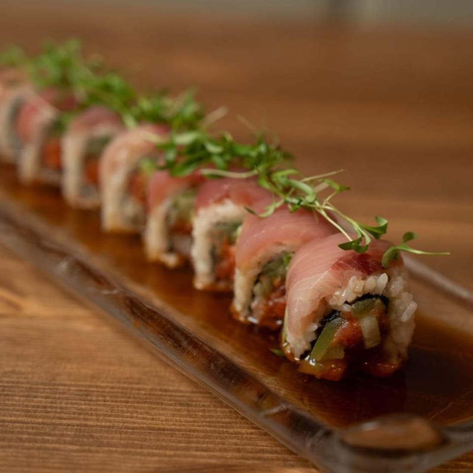 Niko Niko Sushi's tuna sushi roll, garnished with microgreens, served on a rectangular glass plate.