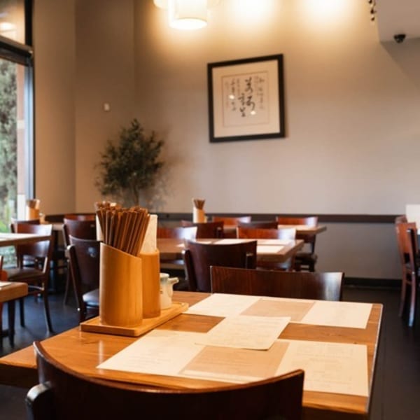 Interior of Niko Niko Sushi restaurant with wooden tables, chairs, and chopsticks on tables.