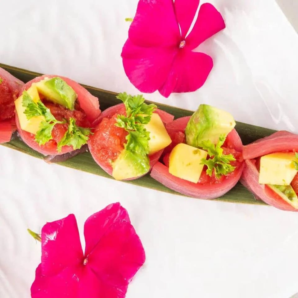 Niko Niko Sushi's tuna rolls with avocado, mango, and parsley, garnished with pink flowers.